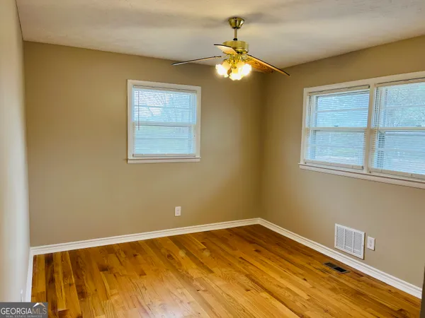 a view of an empty room with wooden floor and a window