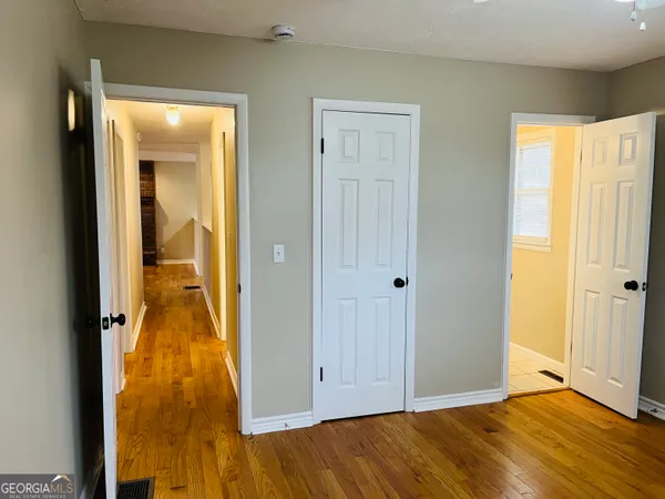 a view of a hallway with wooden floor and a bathroom
