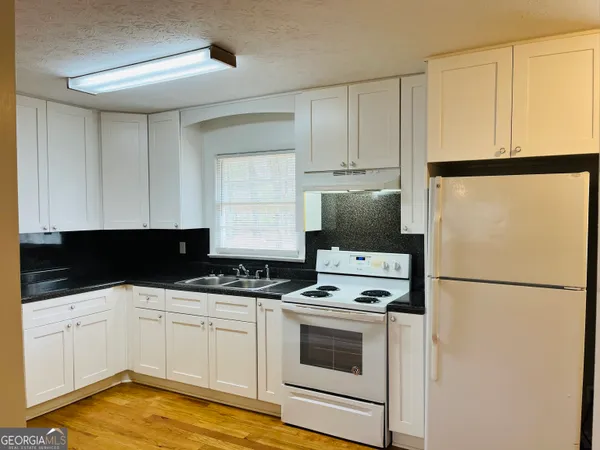 a kitchen with stainless steel appliances a refrigerator sink and white cabinets