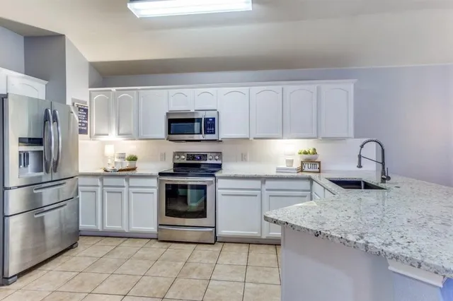 a kitchen with granite countertop a sink and stainless steel appliances