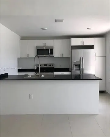 a kitchen with stainless steel appliances a sink a stove a microwave a sink and cabinets