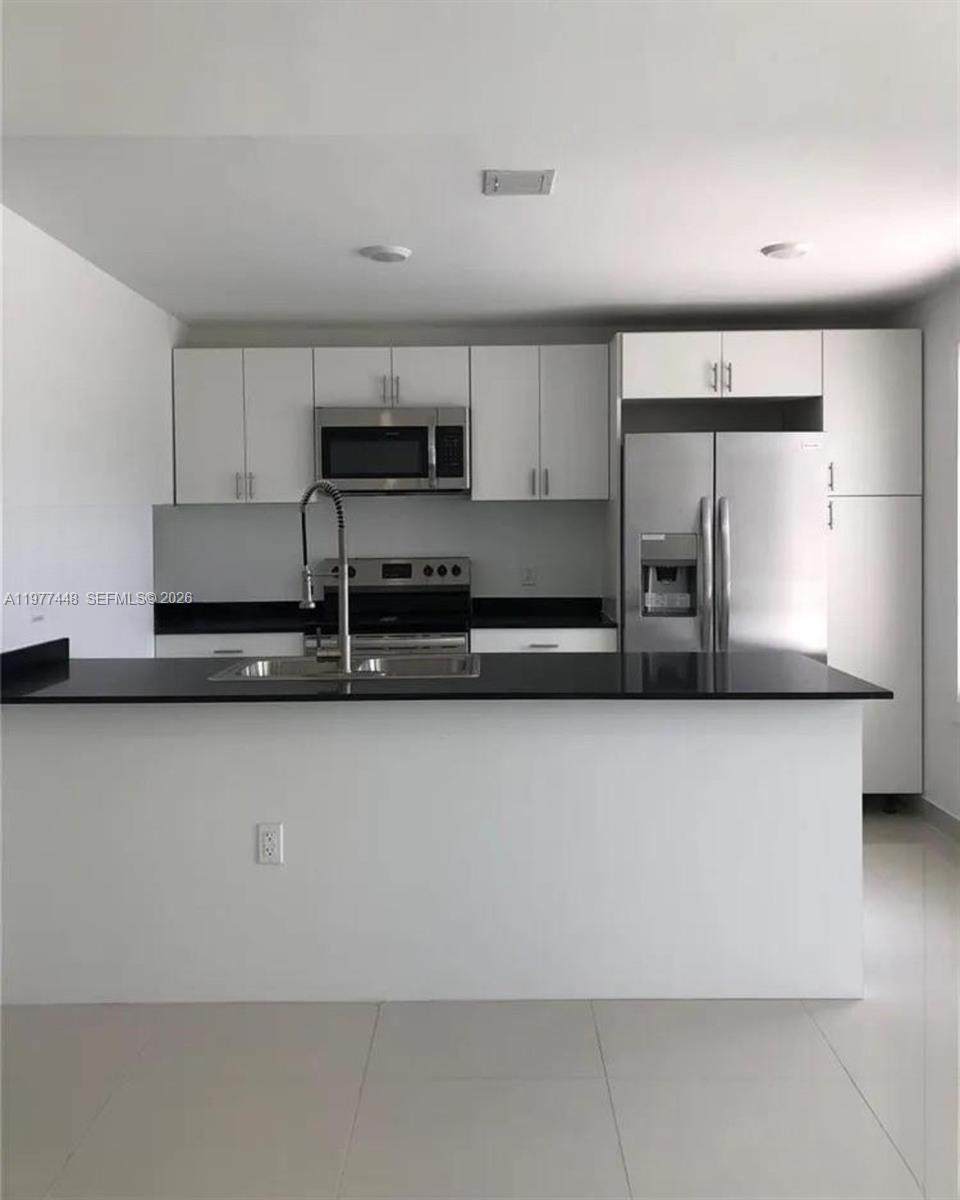 25869 Southwest 139th Path Homestead, FL 33032 - Photo 12 of 17 a kitchen with stainless steel appliances a sink a stove a microwave a sink and cabinets