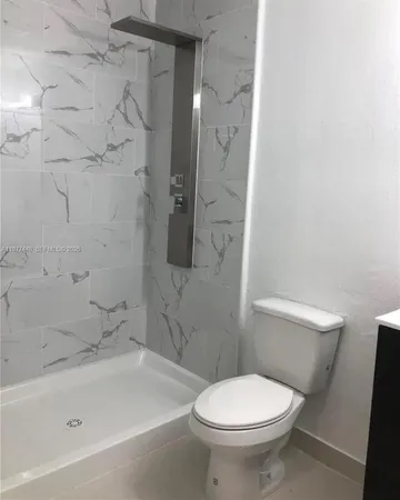 a white toilet sitting next to a bath tub and a shower