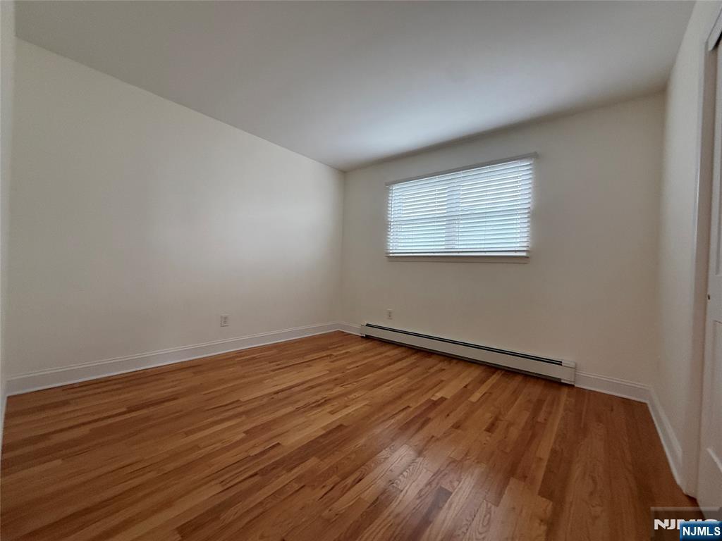 234 Wheeler Street, Unit 2 Cliffside Park, NJ 07010 - Photo 6 of 9 a view of an empty room with wooden floor and a window