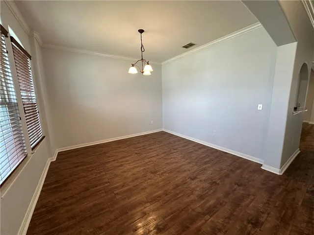 an empty room with wooden floor and chandelier