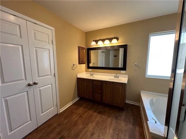 a bathroom with a sink a mirror and wooden floor