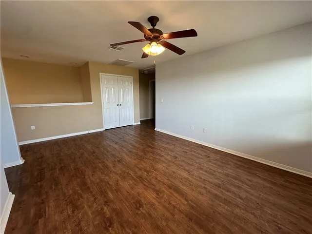 an empty room with wooden floor and ceiling fan