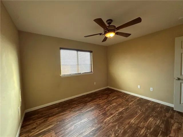 a view of an empty room with window and chandelier fan