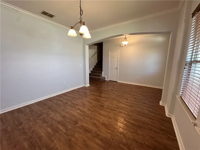 a view of an empty room with wooden floor and windows