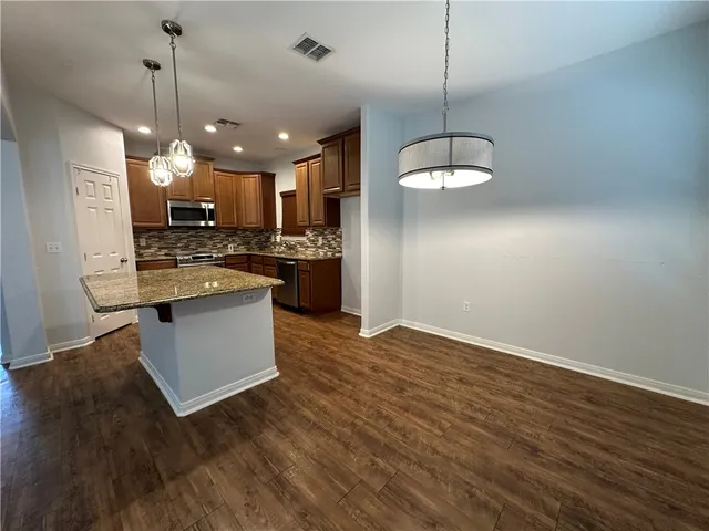a kitchen with stainless steel appliances granite countertop wooden floors sink and cabinets