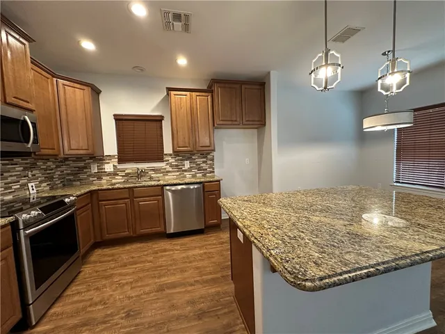 a kitchen with kitchen island granite countertop wooden cabinets and a refrigerator