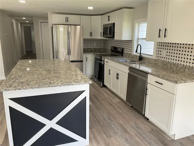 a kitchen with stainless steel appliances granite countertop a sink stove and refrigerator