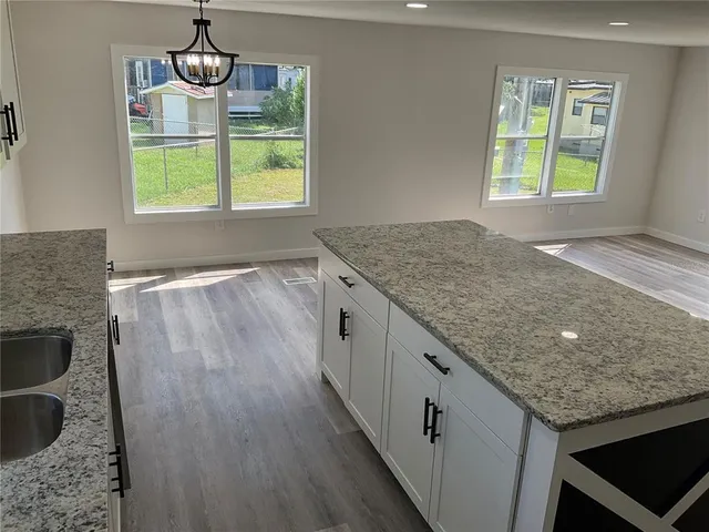 a kitchen with kitchen island granite countertop a stove and a white cabinets