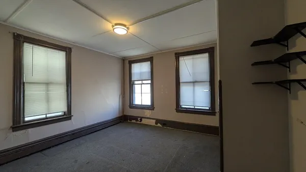 a view of a bedroom with wooden floor and windows