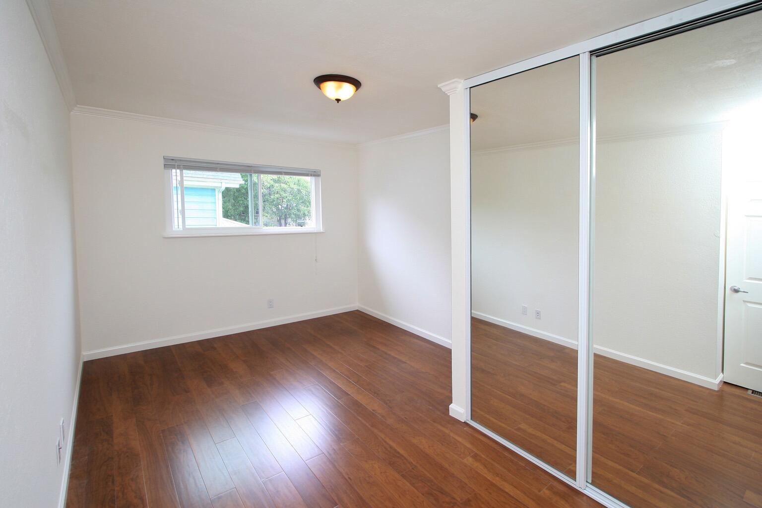 415 Rancheria Street, Unit 4 Santa Barbara, CA 93101 - Photo 8 of 9 an empty room with wooden floor and windows