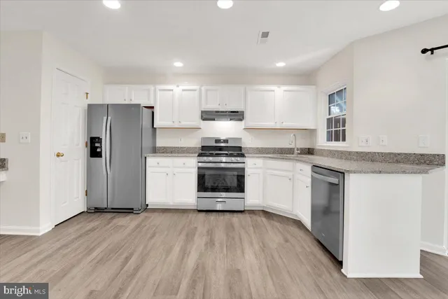 a kitchen with a refrigerator and white cabinets