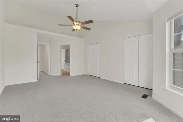 a view of an empty room with chandelier fan