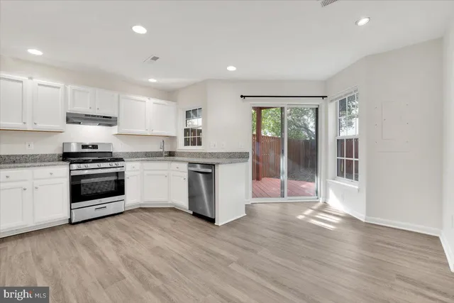 a kitchen with a white cabinets and wooden floor