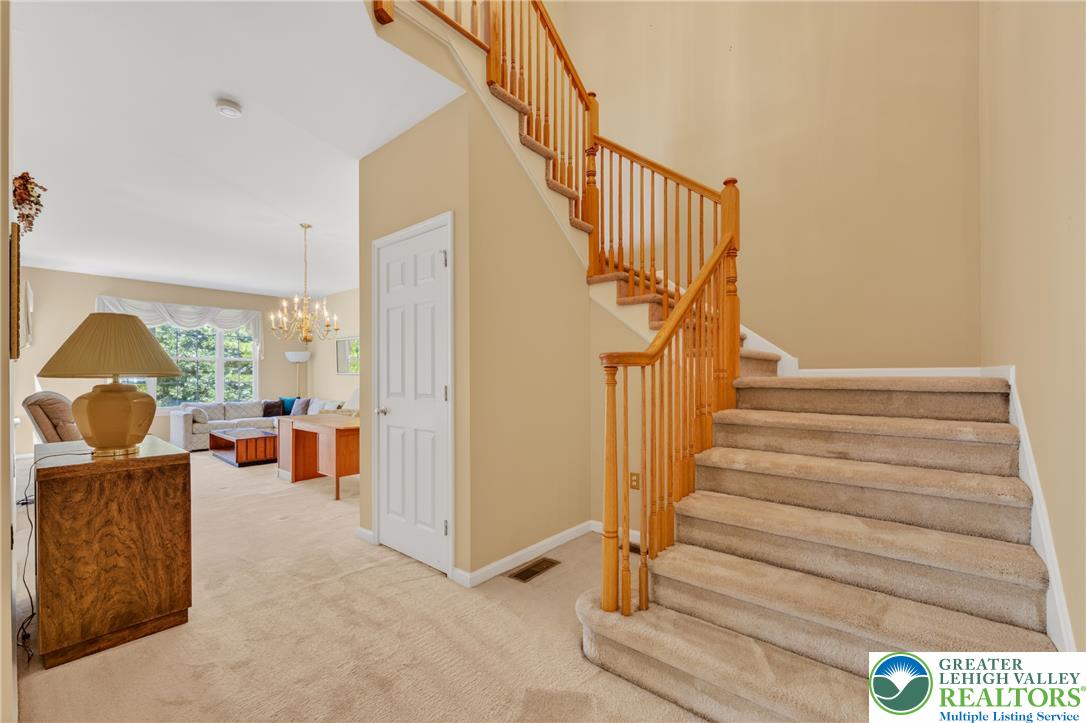 4345 Creek Road Allentown, PA 18104 - Photo 13 of 33 A grand staircase with rich wooden railings greets you upon entry, leading to a naturally illuminated living area.