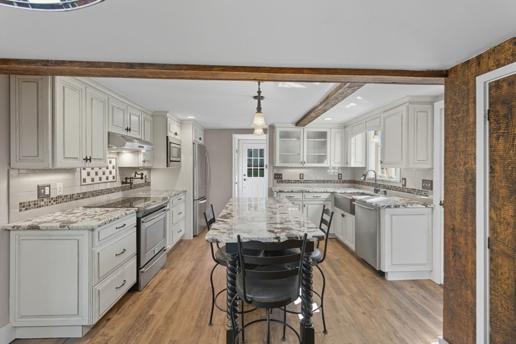 227 Boston Road Groton, MA 01450 - Photo 12 of 42 a kitchen with kitchen island granite countertop a sink cabinets and wooden floor
