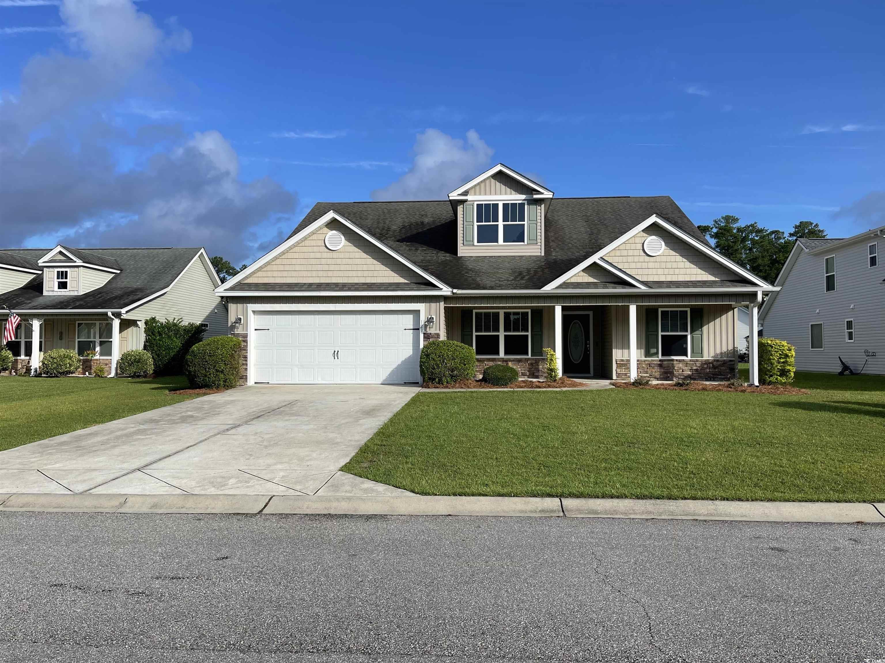 Craftsman inspired home featuring stone siding, driveway, a front yard, and a garage