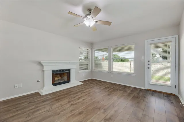 an empty room with windows fireplace and fan