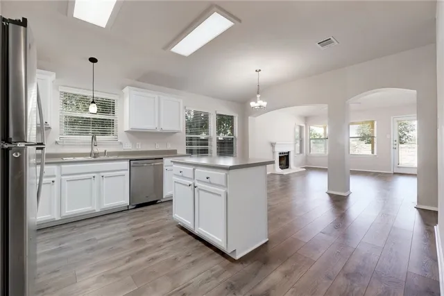 a kitchen with stainless steel appliances sink cabinets and wooden floor
