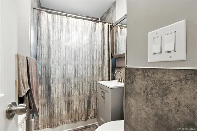 a bathroom with a sink a toilet a mirror and shower curtain