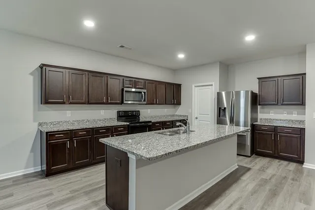 a kitchen with stainless steel appliances granite countertop a stove top oven a sink and dishwasher a refrigerator with wooden floor