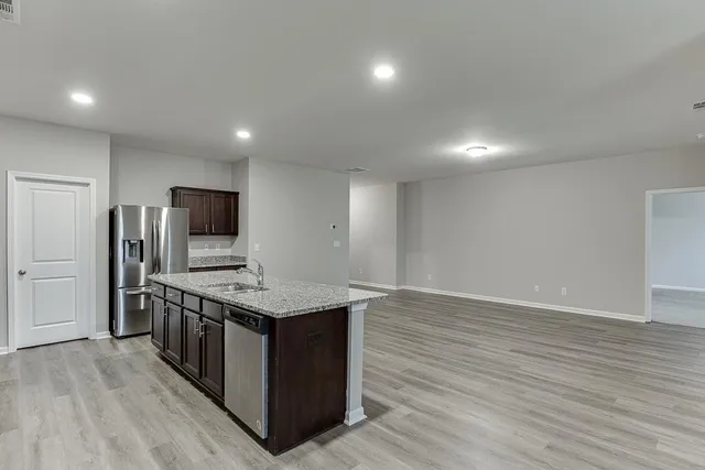 a kitchen with stainless steel appliances a kitchen island hardwood floor sink stove refrigerator and wooden floor