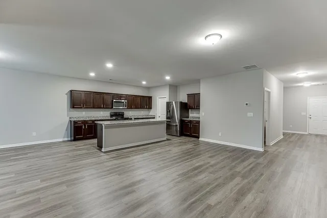 a kitchen with stainless steel appliances kitchen island wooden floors and white counter top