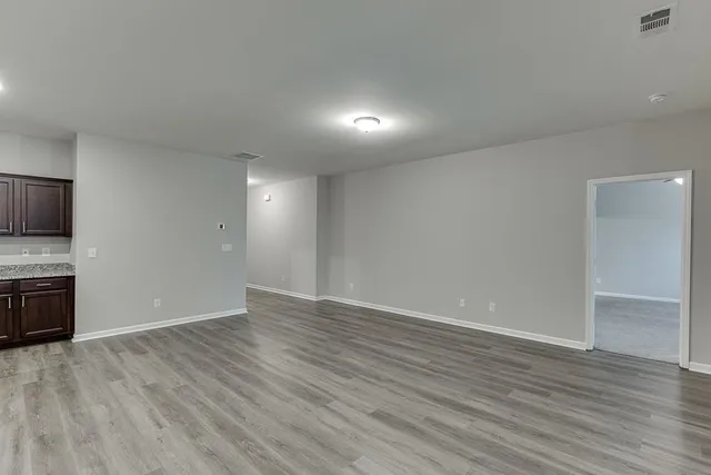 a view of an empty room with wooden floor and a fireplace