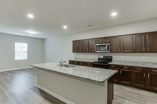 a kitchen with stainless steel appliances granite countertop a sink stove and microwave