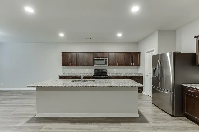 a large kitchen with granite countertop a large counter top stainless steel appliances and cabinets