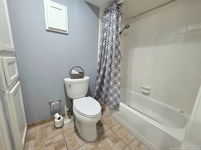 a white toilet sitting next to a bath tub and a shower