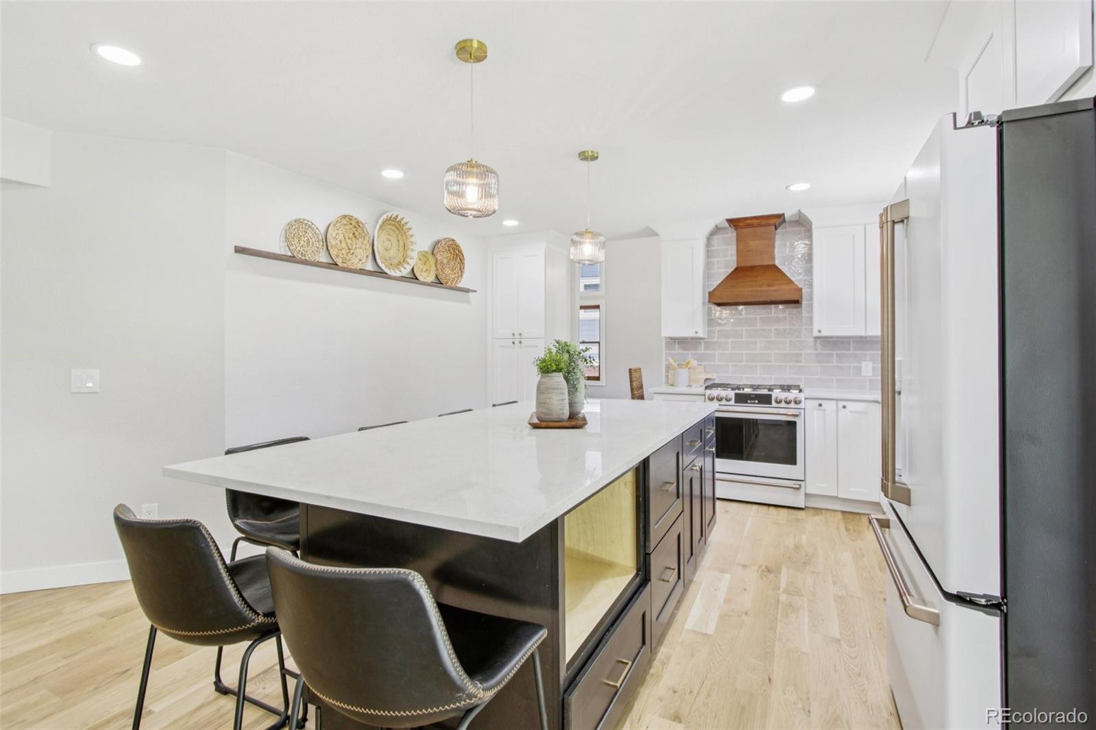 9810 Venneford Ranch Road Highlands Ranch, CO 80126 - Photo 12 of 50 a kitchen with stainless steel appliances kitchen island granite countertop a table chairs and a refrigerator