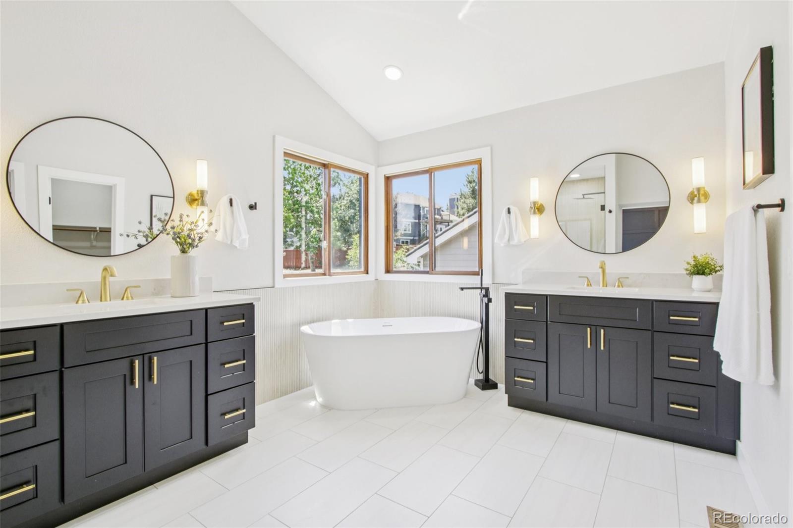9810 Venneford Ranch Road Highlands Ranch, CO 80126 - Photo 24 of 50 a spacious bathroom with a double vanity sink a mirror a bathtub and a window