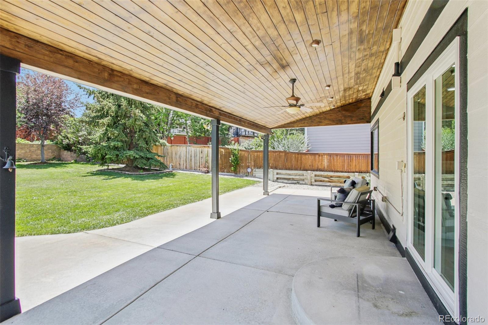9810 Venneford Ranch Road Highlands Ranch, CO 80126 - Photo 39 of 50 a view of a patio with table and chairs under an umbrella with a big yard