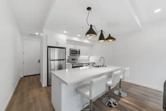 a kitchen with stainless steel appliances a sink a stove a refrigerator and wooden floor