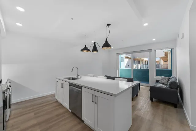 a kitchen that has a sink and a stove with wooden floor