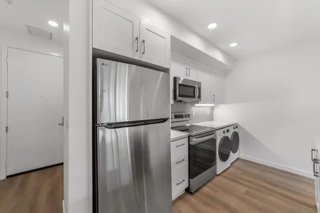 a kitchen with stainless steel appliances a refrigerator a stove a microwave and white cabinets