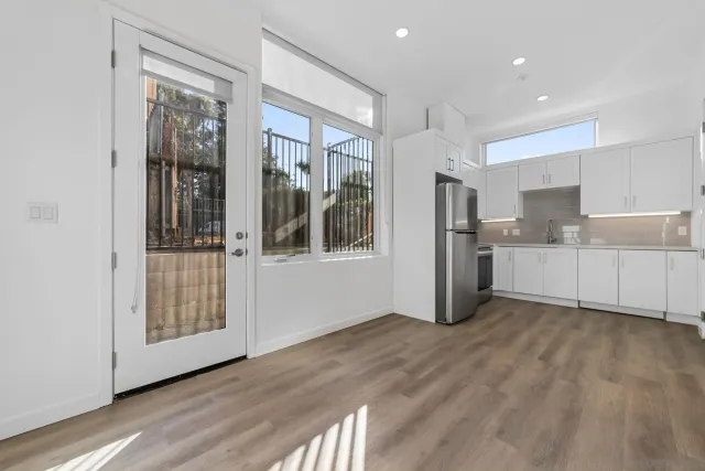 a view of a kitchen with a fridge and wooden floor