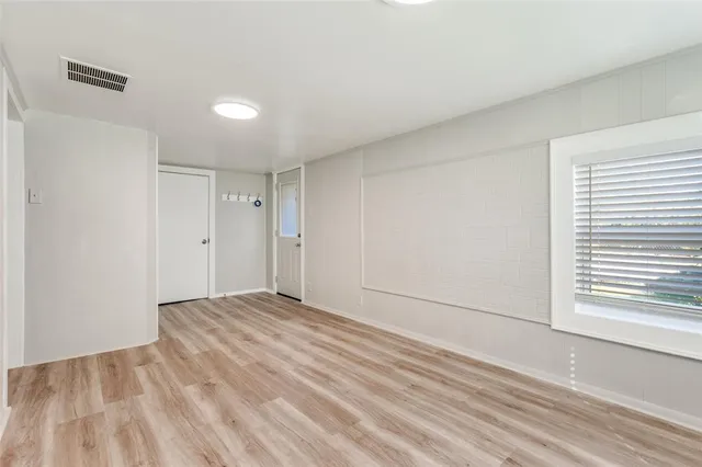a view of an empty room with wooden floor and a window