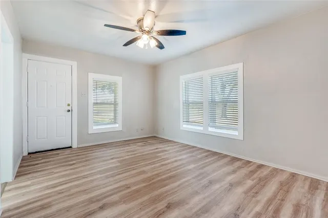 a view of an empty room with a window and wooden floor