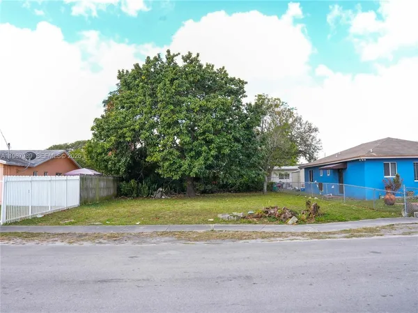 a view of a house with a big yard and large trees