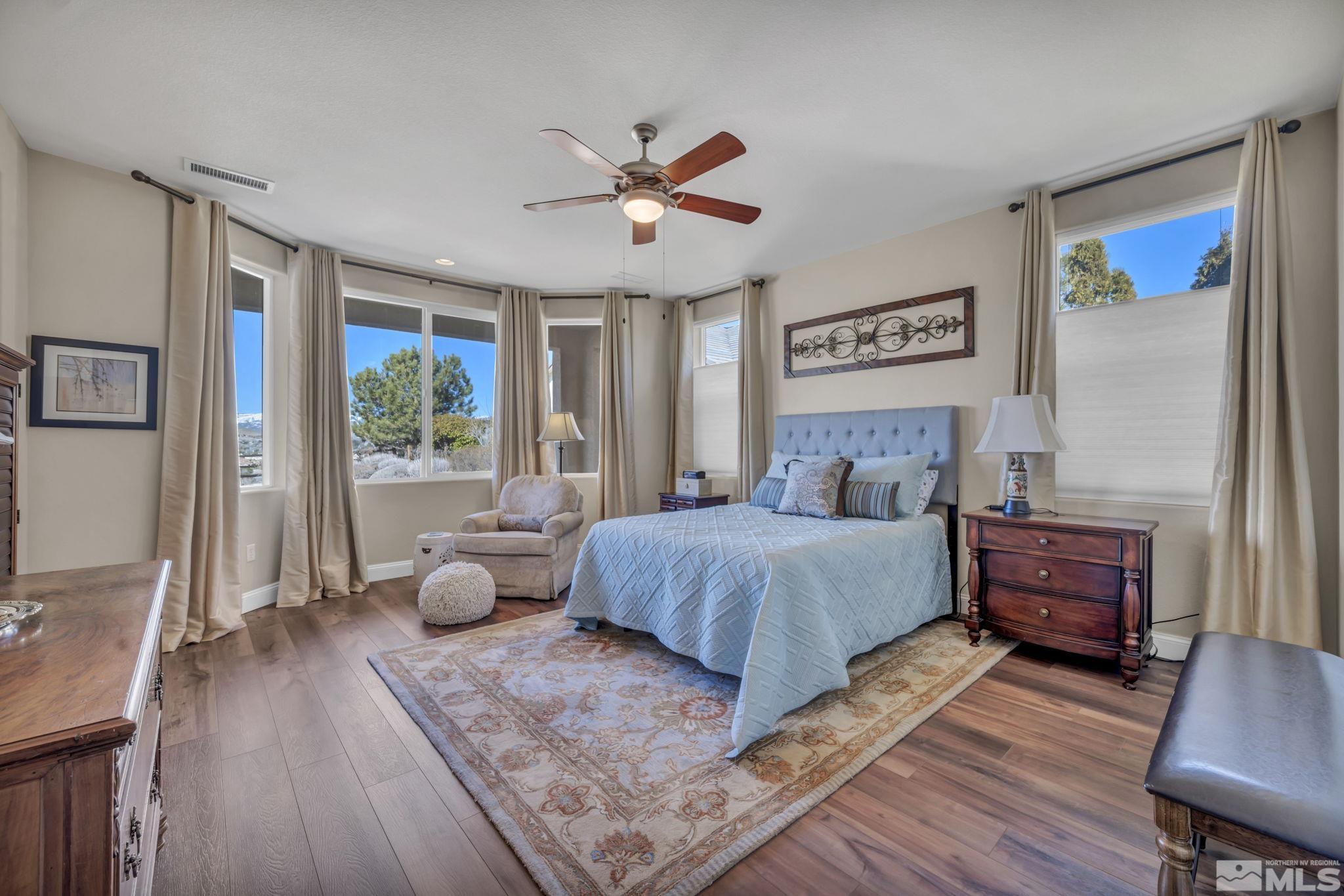 1479 Snow Summit Drive Reno, NV 89523 - Photo 14 of 40 a bedroom with a large bed a large window with wooden floor