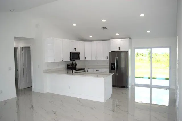 a kitchen with refrigerator and a view of living room