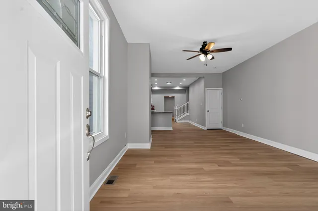 a view of a hallway view with wooden floor and a ceiling fan