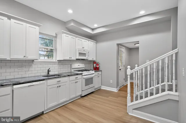 a kitchen with stainless steel appliances granite countertop a sink and cabinets with wooden floor