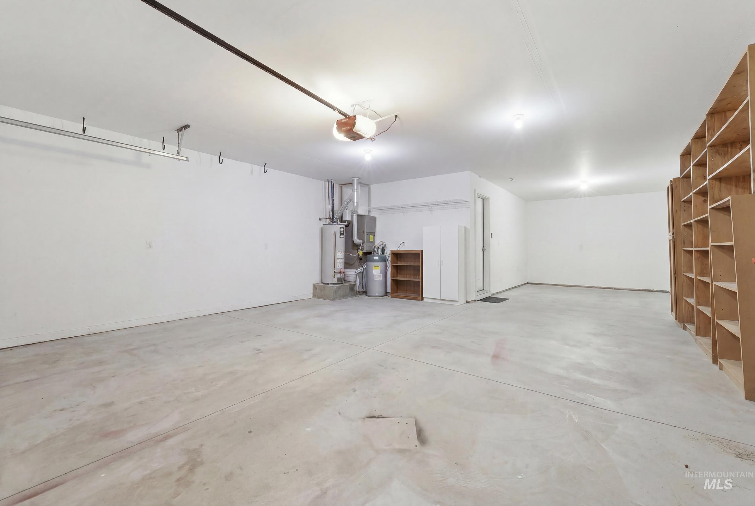 4855 South Chex Way Boise, ID 83709 - Photo 40 of 47 Spacious garage featuring a concrete floor, built-in shelving, white painted walls, and overhead lighting